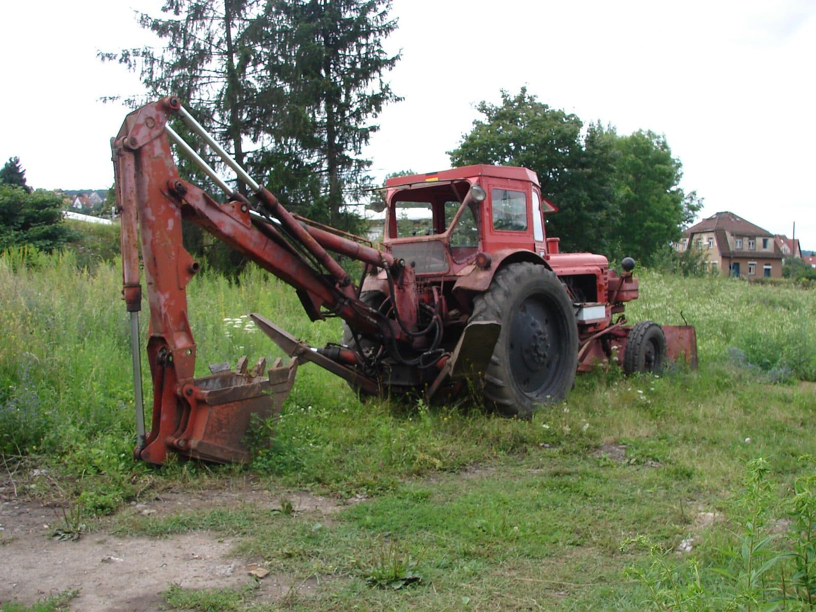 Retroexcavadora con brazo trasero en un terreno con césped